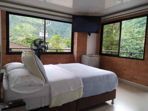 a bedroom with a bed with two large windows at Hotel el peñón in Santa María