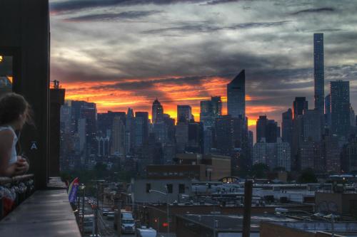a woman standing on a balcony looking at a city skyline at The Local NY in Queens