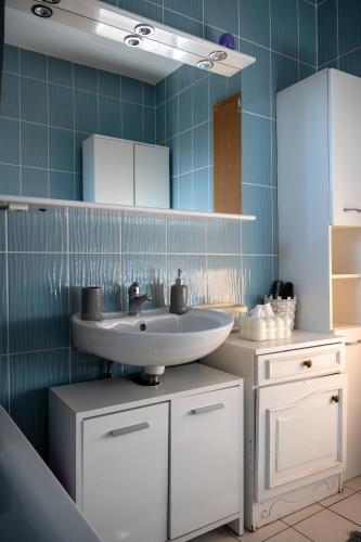 a bathroom with a sink and a blue tiled wall at Apartman Jedro in Vukovar