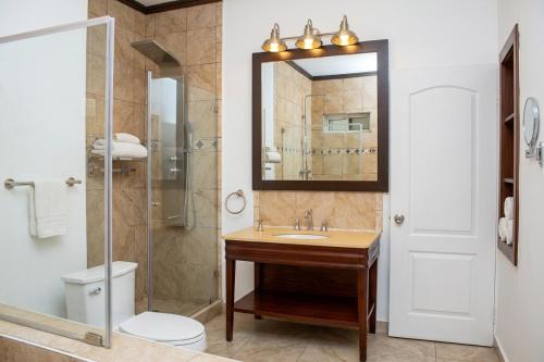 a bathroom with a sink and a toilet and a mirror at The Jam Lodge in Freetown
