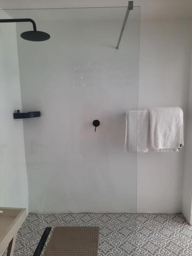 a bathroom with white walls and a shower with towels at Berg and Dal in Paarl