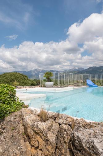 a large swimming pool with a fence and mountains at Residence Verdeluna in Marina di Pietrasanta
