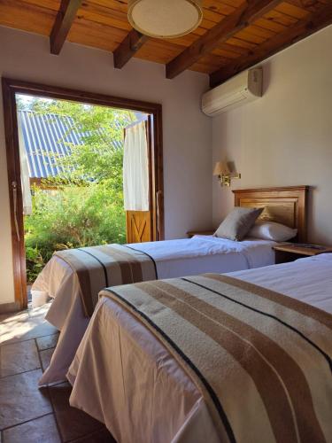 two beds in a room with a large window at Ayelen Andina in Esquel