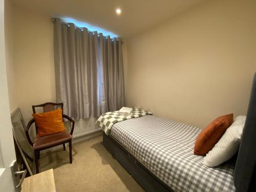 a bedroom with a bed and a chair and a window at Modern 2 bed ground floor flat in Watford