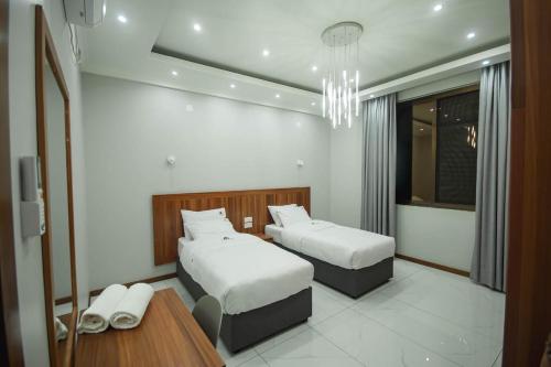 a bedroom with two beds and a table and a chandelier at Ultra Aparthotel in Tete