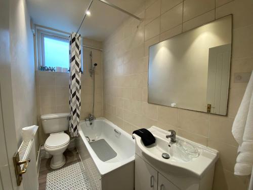 a bathroom with a sink and a toilet and a tub at Modern 2 bed ground floor flat in Watford