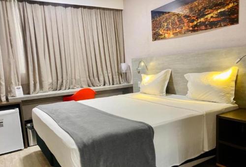 a bedroom with a large white bed and a window at Nord Luxxor Citymix in Campina Grande