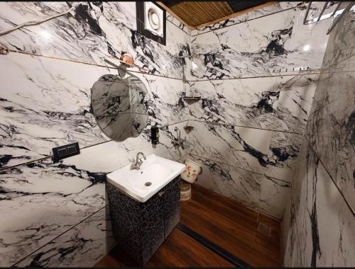a bathroom with a sink and a marble wall at Hotel First Impression in Rāmnagar