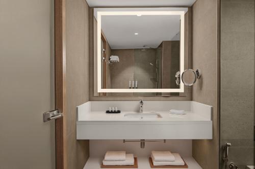 a bathroom with a white sink and a mirror at Courtyard by Marriott Dakar Diamniadio in Dakar