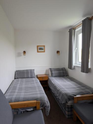 two twin beds in a room with a window at Scoor House - Cnoc Mor in Bunessan