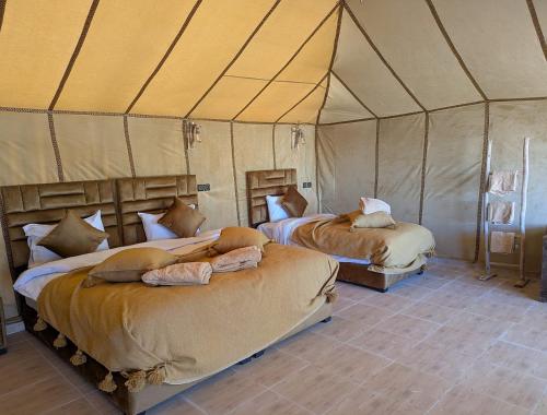 a bedroom with two beds in a tent at Grand Dunes Luxury Camp in Merzouga