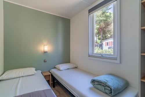 two beds in a room with a window at Camping Valras plage 5 étoiles in Vendres