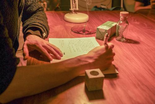 a person sitting at a table writing on a paper at Local Knot Backpackers in Nagano