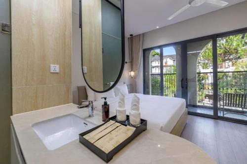 a bathroom with a sink and a bed and a mirror at Soluna Dalat Hotel in Da Lat