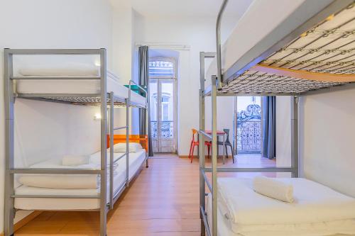 a room with three bunk beds and a table at HI Tavira – Pousada de Juventude in Tavira