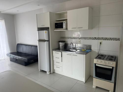 a small kitchen with white cabinets and a refrigerator at Apartamento 70 metros do mar in Florianópolis