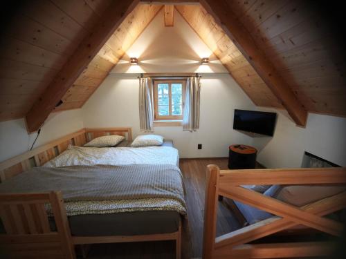 a attic bedroom with two beds and a television at Roubenka a miniroubenka, Olšany in Olšany