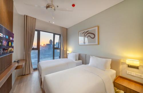 a hotel room with two beds and a window at Soluna Dalat Hotel in Da Lat