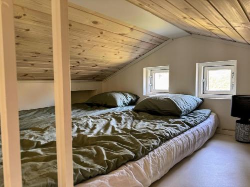 a bed in a room with a wooden ceiling at Central, Modern, Cozy Cottage in Gävle