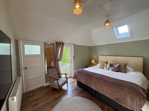a bedroom with a bed and a chair and a window at Willows Cottage in Pitlochry