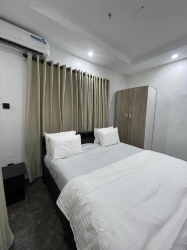 a bedroom with a large bed with white sheets and pillows at Kennys place in Isaga-Abosule