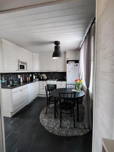 a kitchen with white cabinets and a table and chairs at Faamos Loviisa in Loviisa