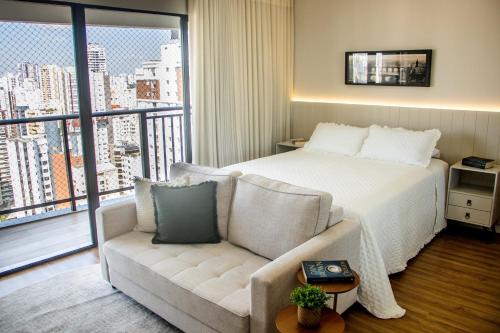 a bedroom with a bed and a couch and a window at Opus Gyro Vaca Brava Studio Luxo e Aconchego in Goiânia