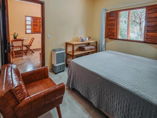 a bedroom with a bed and a chair at Chalés Refúgio da Sil 2 in Cavalcante