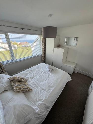 a bedroom with a large white bed with a window at 34 Surfview Beach House in Newquay