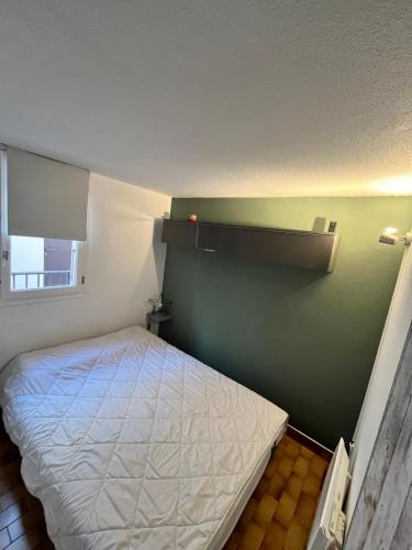 a small bedroom with a bed and a green wall at Vacances Cap d'Agde 1 chambre, 1 mezzanine, parking et piscine in Cap d'Agde