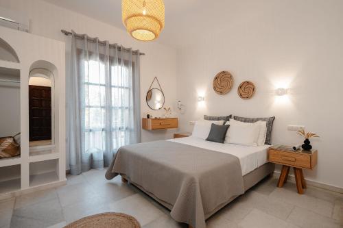 a white bedroom with a large bed and a window at Katerina Studios in Naxos Chora