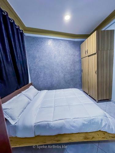 a small bedroom with a bed and a wooden cabinet at Speke homes full apartment!!! in Kabale