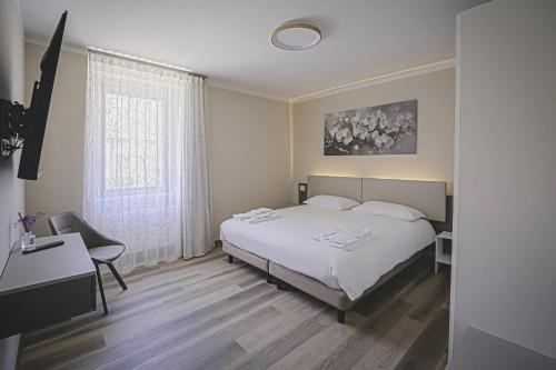 a bedroom with a bed and a desk and a window at CuorNice - LG Estate in Ripe San Ginesio