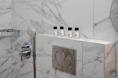 a bathroom with white marble walls and a shower with three bottles at Katerina Studios in Naxos Chora