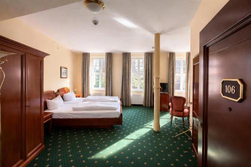 a hotel room with a bed and a chair at Schlossparkhotel Schkopau in Schkopau