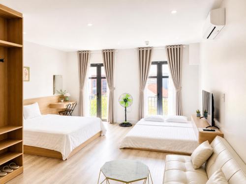 a bedroom with two beds and a couch at Fame Apartment in Dong Hoi