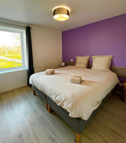 a bedroom with a large bed with a purple wall at Gîte Les Cèdres in Pommiers