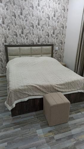 a bedroom with a large bed with a ottoman and a wall at Bnakaran dzoragetum in Dzoraget
