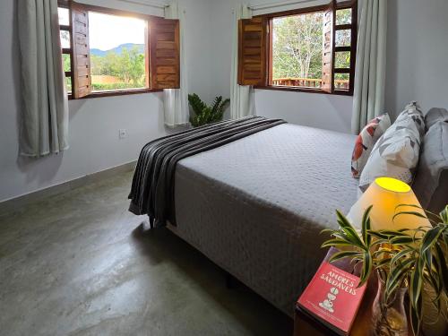 a bedroom with a bed and two windows at Chalés Refúgio da Sil in Cavalcante