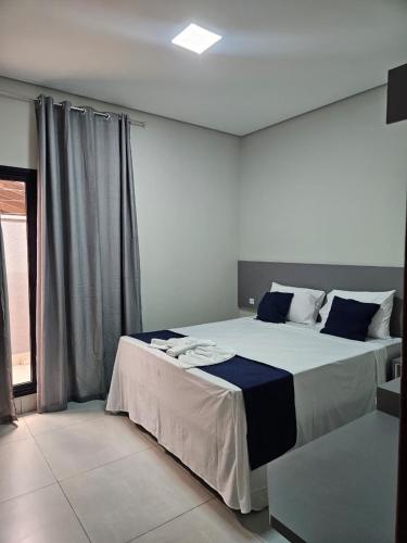 a bedroom with a large bed with blue and white sheets at Melges Apart Hotel in Pontes e Lacerda