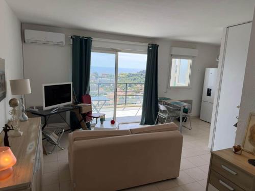 a living room with a couch and a desk with a computer at Studio climatisé avec vue mer in Bastia