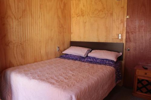 ein kleines Schlafzimmer mit einem Bett mit Holzwänden in der Unterkunft Departamentito Austral in Puerto Montt