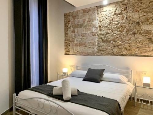 a bedroom with a white bed with a stone wall at Homenfun Vila Badalona in Badalona