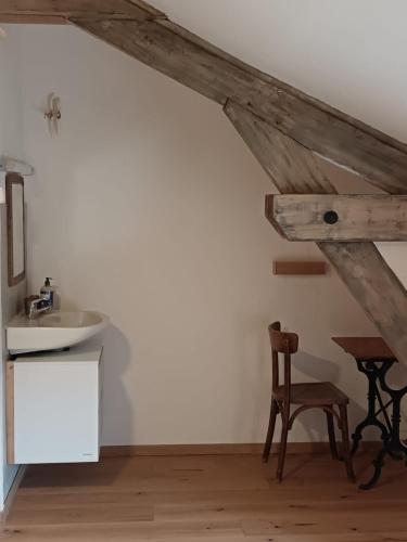a bathroom with a sink and a table and a chair at Auberge de Lagrand in Lagrand