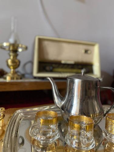 a silver tea pot and cups on a glass tray at Dar hania in Tozeur