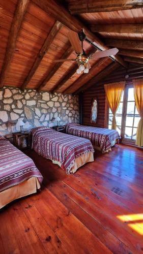 a bedroom with two beds and a stone wall at Aypa Pacha Nono in Nono