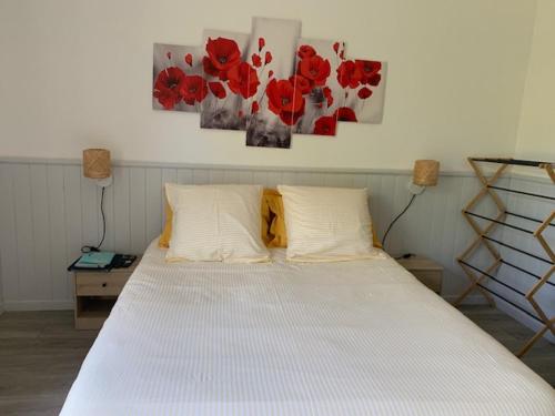 a bedroom with a white bed with red flowers on the wall at Un peu de campagne in Saint-Gilles-de-la-Neuville