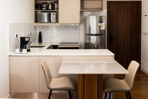 a kitchen with a white counter and two chairs at Steps from the Shopping del Sol! in Asunción