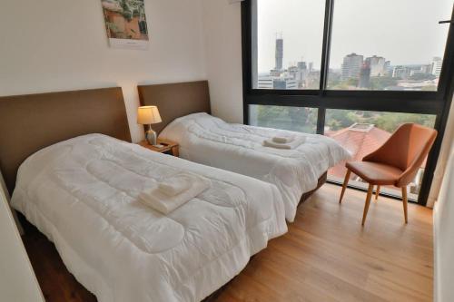two beds in a room with a large window at Large Apartment Just Steps from Shopping del Sol in Asunción