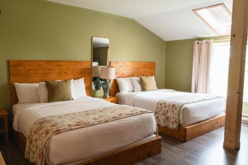 a bedroom with two beds and a mirror at Auberge la Rosepierre bistro Henri in Grandes-Bergeronnes